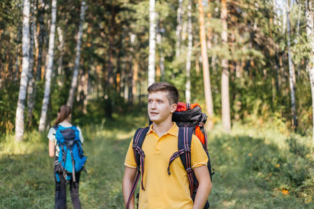 couple of tourists with backpacks hiking in a forest