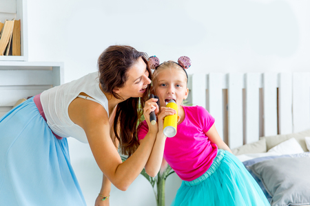 Mother and her little daughter sing into the microphone togetherの写真素材