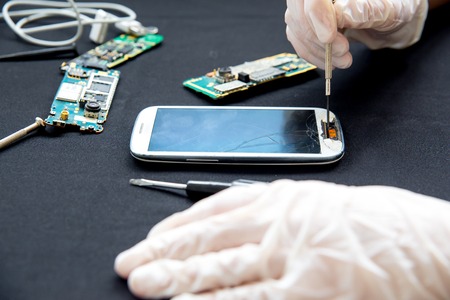 Electronics repair service - technician is fixing broken cell phoneの写真素材