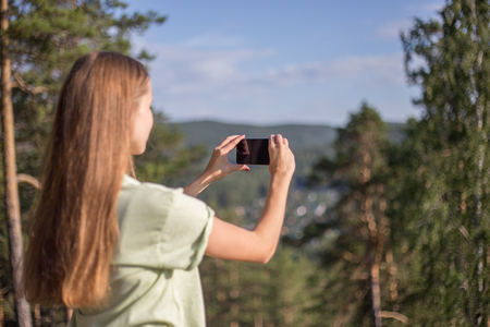 hiker is taking a photo on a mountain with a cell phoneの写真素材