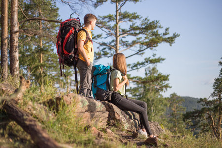 couple of tourists with backpacks hiking up a mountain