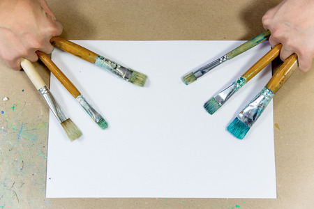 several paintbrushes with paint on a tableの写真素材