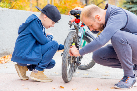 father and his son fixing bike in a parkの写真素材