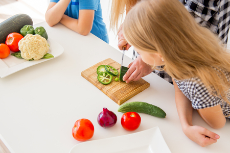 Young pregnant woman in the kitchen at home cooking saladの写真素材