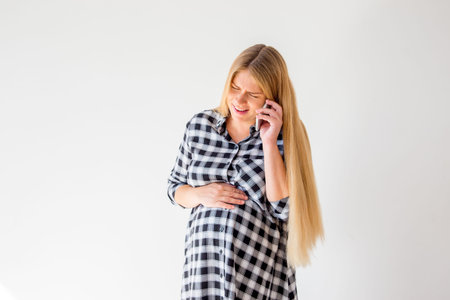 Pregnant woman talking on a mobile phone at home