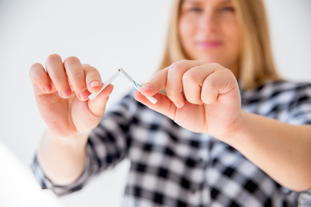 Young pregnant woman breaking a cigarette - healthy pregnanc conceptの写真素材