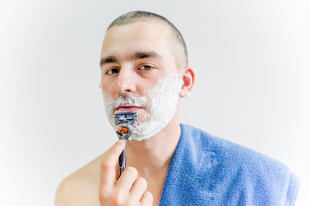 man is shaving his face in a bathroomの写真素材