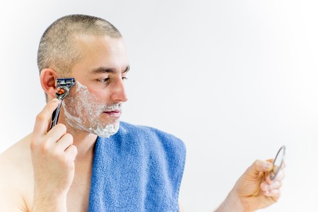 man is shaving his face in a bathroomの写真素材