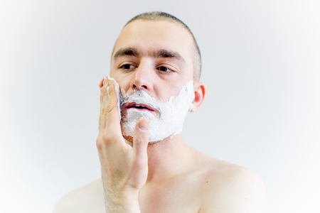 man is shaving his face in a bathroomの写真素材