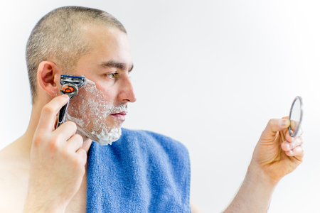 man is shaving his face in a bathroomの写真素材