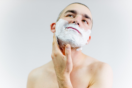 man is shaving his face in a bathroomの写真素材