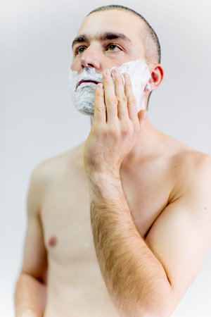 man is shaving his face in a bathroom