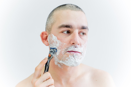 man is shaving his face in a bathroomの写真素材