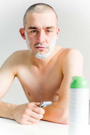 man is shaving his face in a bathroomの写真素材