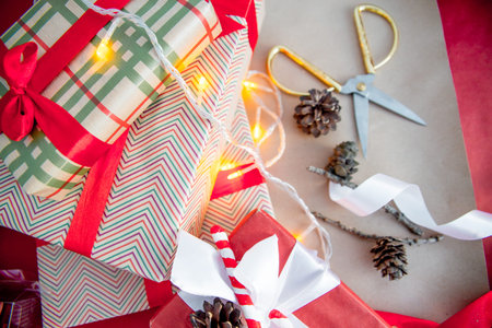 Female hands wrapping red christmas gift boxes