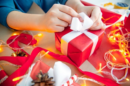 Female hands wrapping red christmas gift boxesの写真素材
