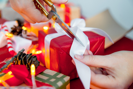 Female hands wrapping red christmas gift boxesの写真素材