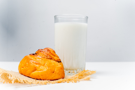 a glass of milk with bread and grainsの写真素材