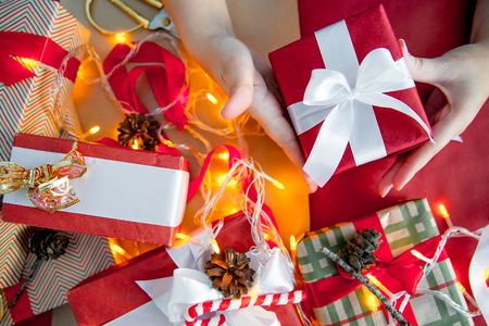 Female hands wrapping red christmas gift boxesの写真素材