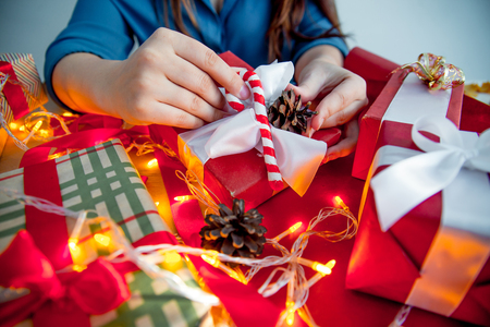 Female hands wrapping red christmas gift boxesの写真素材