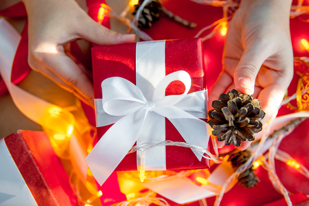 Female hands wrapping red christmas gift boxesの写真素材