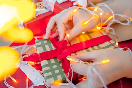 Female hands wrapping red christmas gift boxesの写真素材