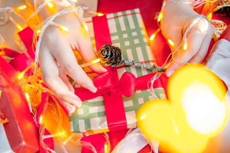 Female hands wrapping red christmas gift boxesの写真素材