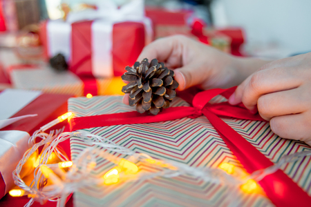 Female hands wrapping red christmas gift boxesの写真素材