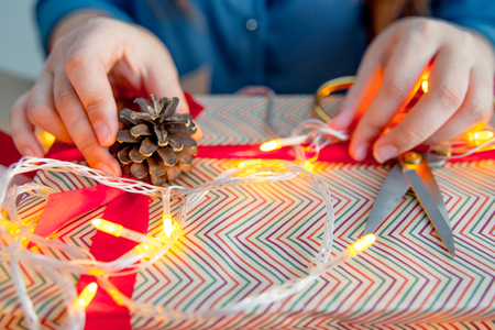 Female hands wrapping red christmas gift boxesの写真素材