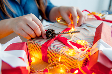 Female hands wrapping red christmas gift boxesの写真素材