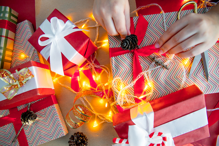 Female hands wrapping red christmas gift boxesの写真素材