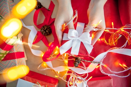 Female hands wrapping red christmas gift boxesの写真素材
