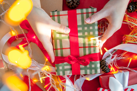 Female hands wrapping red christmas gift boxesの写真素材