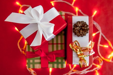 Female hands wrapping red christmas gift boxesの写真素材