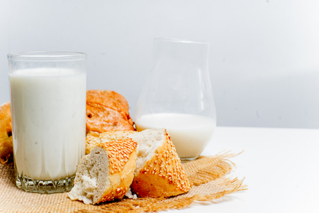 a glass of milk with bread and grainsの写真素材