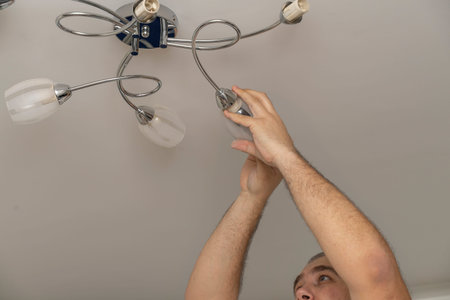 man changes the light bulb in the lighting device. husband for an hour