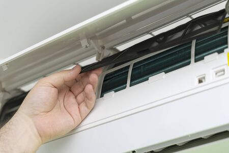 Male technician repairing and reading air conditioners. Opening the cover and cleaning the right filterの写真素材
