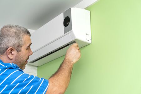 Male technician repairing and diagnosing air conditioners. Diagnostics for errors and preparation of a repair planの写真素材