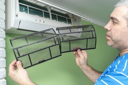 Male technician repairing and reading air conditioners. Cover opening and close-up of two filtersの写真素材