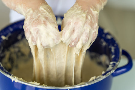 little girl kneads yeast dough in a blue pan, hands closeup.