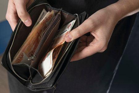 a man with a black wallet full of Russian money. in a black wallet, banknotes are mostly 5,000...