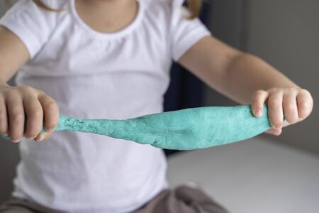 child preschooler stretches a turquoise dough for modeling. quarantine and self-isolation of children's creativityの写真素材