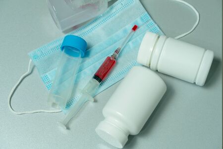 tablets in jars, antiseptic gel, disposable mask, syringe with a red vaccine. development of a vaccine against Covid-19 by scientistsの写真素材