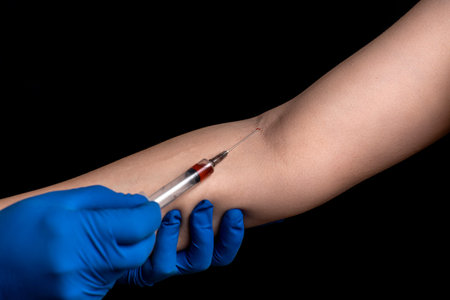 a doctor in disposable gloves takes blood from a patientâ€™s vein for analysis on a black...
