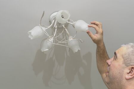 man changes a light bulb in a lighting deviceの写真素材