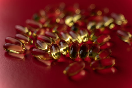 fish oil capsules on a red background close-up with a small roughness of sharpness. blurred background on the theme of healthの写真素材
