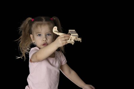 stay home save life text on dark background. sitting next to the floor is a little girl in jeans and playing with a wooden airplane. the need to stay home in the midst of a coronavirus pandemicの写真素材