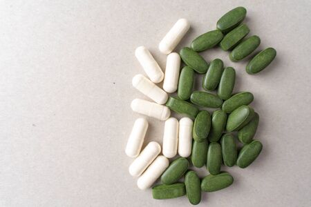 green chlorella pills and white pills on a gray background. nutritional supplements for a healthy dietの写真素材