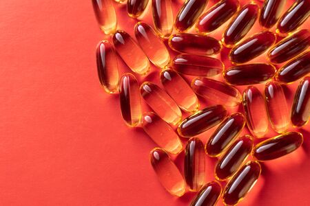 fish oil capsules on red background close-upの写真素材