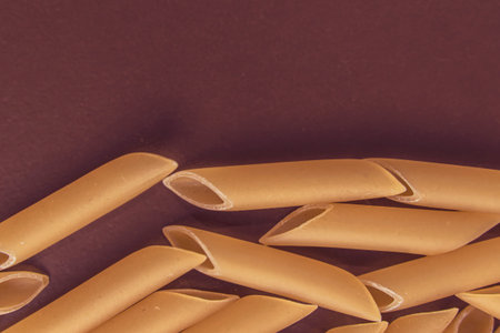 spaghetti and penne, feathers, set of italian pasta on a brown background with copy space. purple...